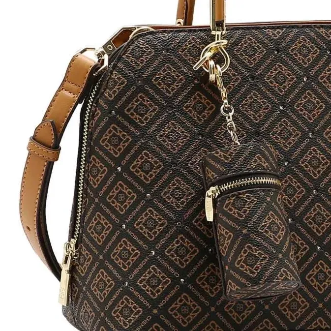 Close lateral da bolsa Chenson cor café mostrando zíper dourado, alças caramelo e textura do material